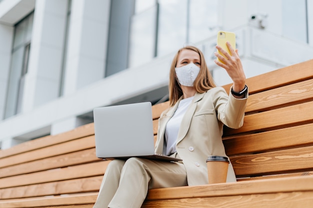 Bella donna in maschera protettiva medica prendendo un selfie