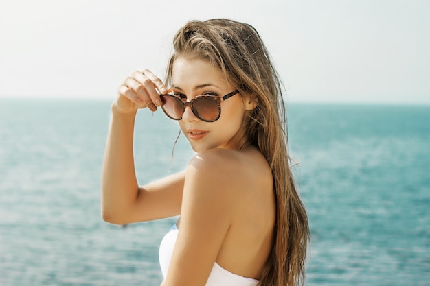 Bella donna in occhiali da sole sulla spiaggia