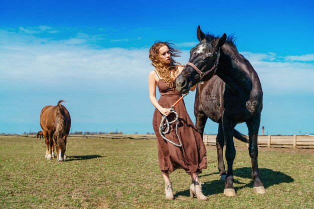 Bella donna in piedi in un campo con un cavallo