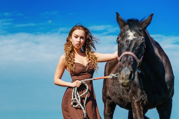 Bella donna in piedi in un campo con un cavallo