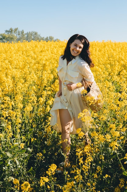 Bella donna in piedi nell'estate del campo di colza