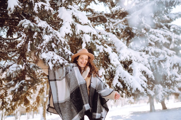 Bella donna in piedi tra alberi innevati e godendo la prima neve. Tempo felice. Natale.