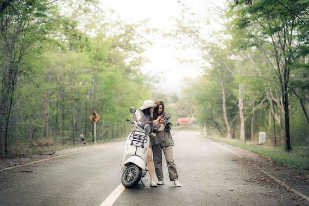 Bella donna in sella a uno scooter su strada Viaggia in scooter con un amico la vita lenta in campagna in vacanza