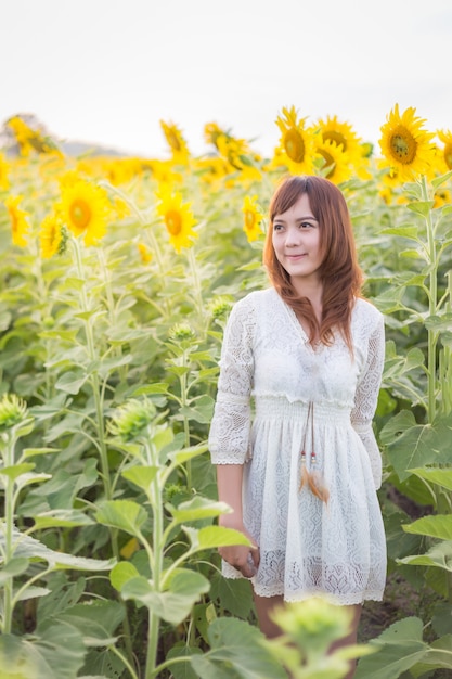 bella donna in un abito bianco su un campo di girasoli estivi