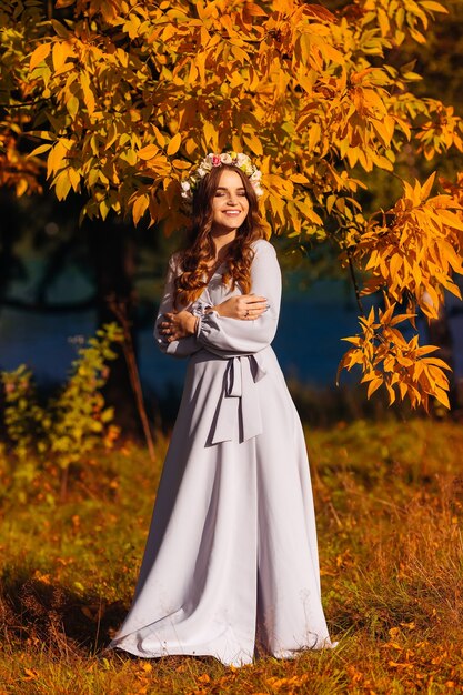 Bella donna in un abito lungo nella foresta di autunno