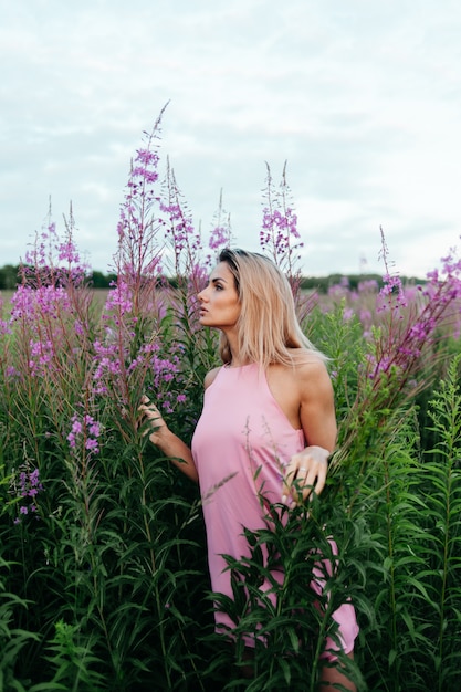 Bella donna in un campo di fiori rosa.