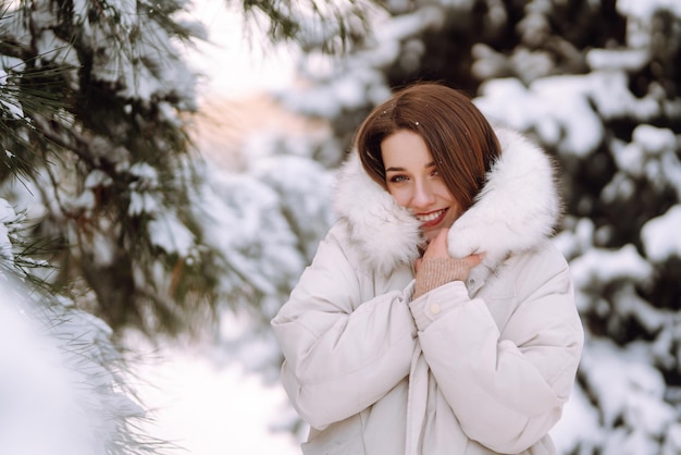 Bella donna in un parco innevato. Giovane donna che cammina in una soleggiata giornata invernale.