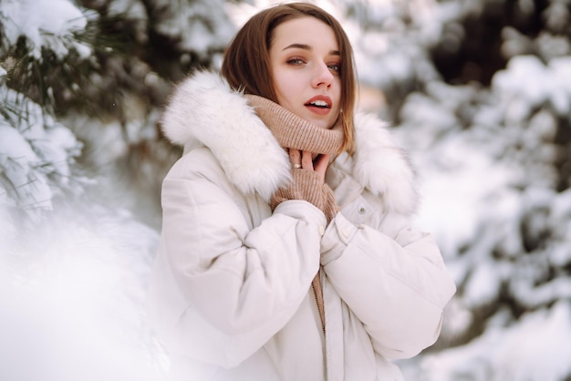 Bella donna in un parco innevato Giovane donna che cammina in una soleggiata giornata invernale