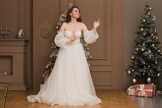 Bella donna in un vestito blu sullo sfondo di un albero di Natale