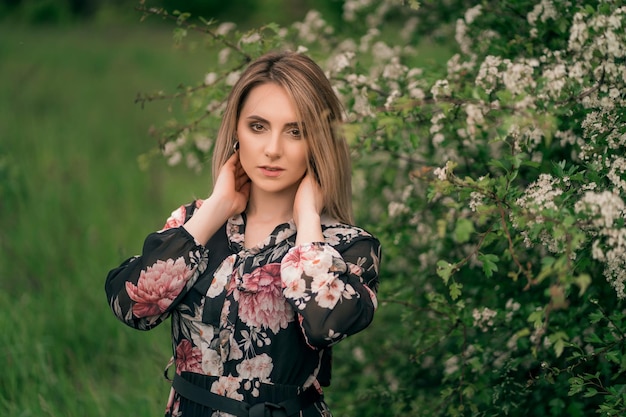 Bella donna in un vestito sulla natura vicino agli alberi in fiore