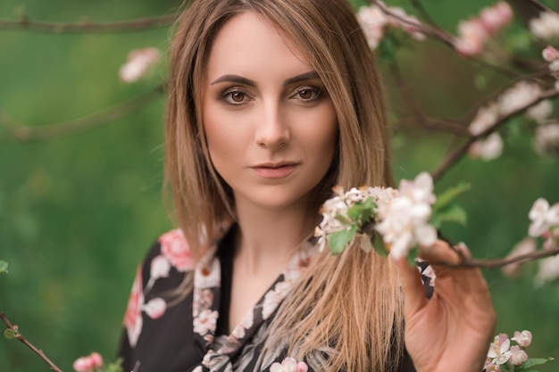 Bella donna in un vestito sulla natura vicino agli alberi in fiore