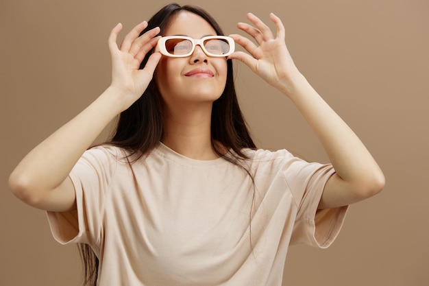 Bella donna in una maglietta beige con gli occhiali in posa modello di studio di abbigliamento moda