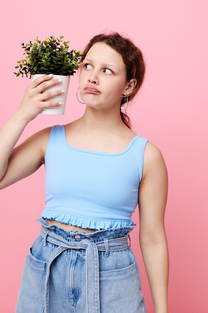 Bella donna in una maglietta blu e pantaloncini uno sfondo rosa vaso di fiori inalterato