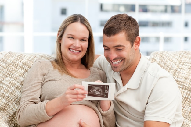 Bella donna incinta che mostra la sua ecografia a suo marito