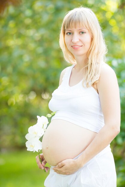 Bella donna incinta con fiore su sfondo verde primavera