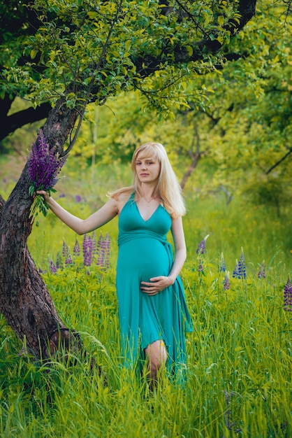 Bella donna incinta con i fiori nel parco.