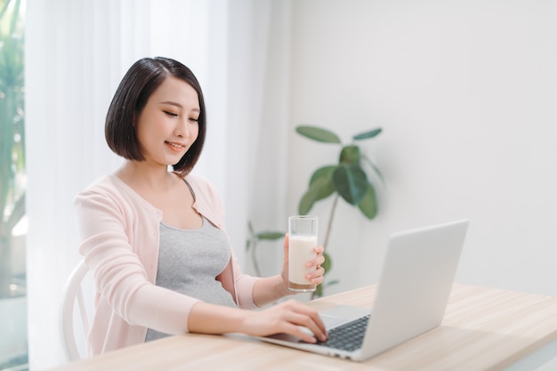 Bella donna incinta con il latte alimentare portatile a casa