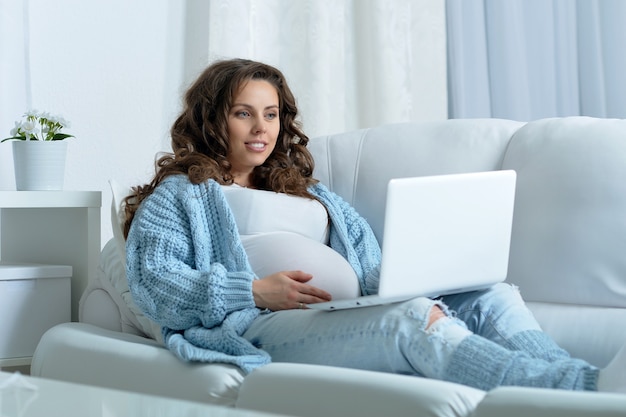 Bella donna incinta con lunghi capelli scuri e laptop