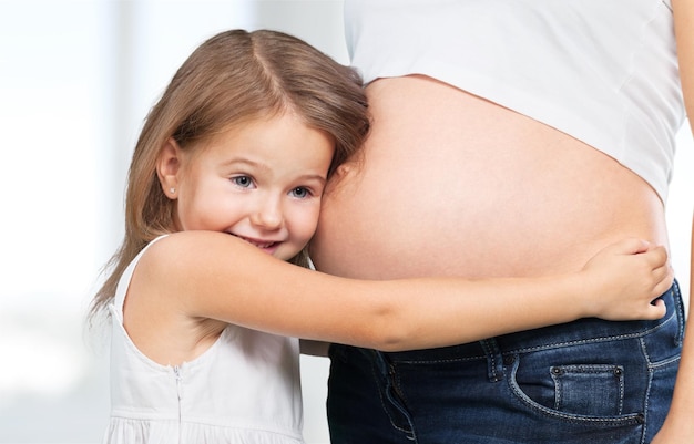 Bella donna incinta con sua figlia. Isolato su sfondo