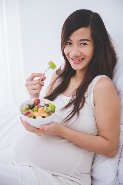 Bella donna incinta con una ciotola di frutta