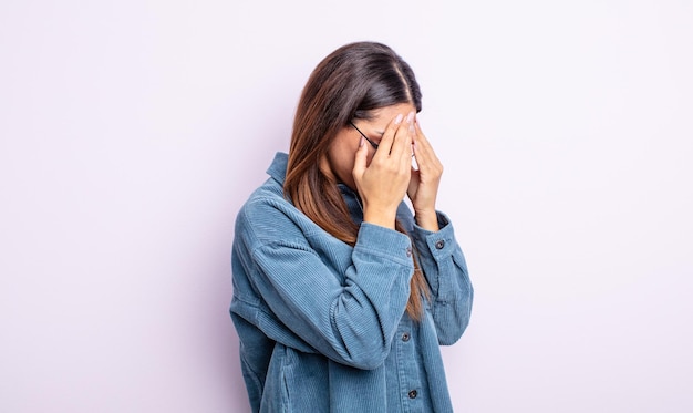 Bella donna ispanica che copre gli occhi con le mani con uno sguardo triste e frustrato di disperazione che piange vista laterale