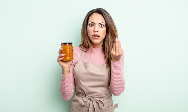 Bella donna ispanica che fa un gesto capice o denaro, dicendoti di pagare. concetto di marmellata di pesche