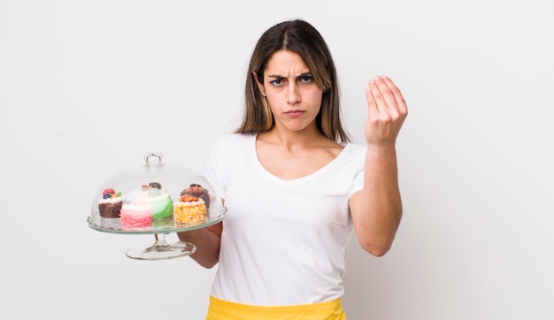 Bella donna ispanica che fa un gesto di capice o denaro che ti dice di pagare il concetto di torte fatte in casa