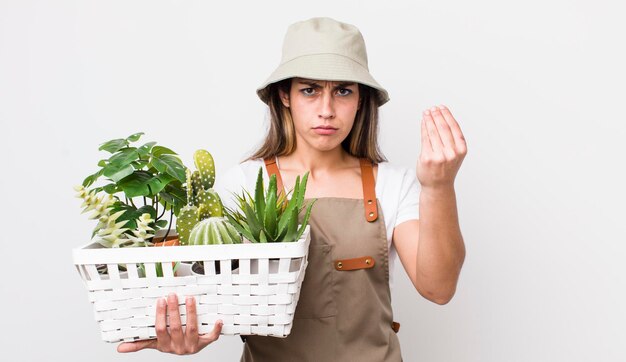 Bella donna ispanica che fa un gesto di capice o denaro che ti dice di pagare le piante e il concetto di giardinaggio