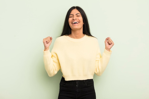 Bella donna ispanica che sembra estremamente felice e sorpresa che celebra il successo gridando e saltando