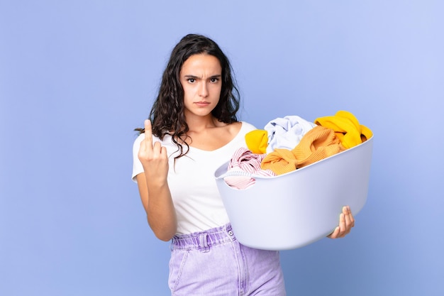 Bella donna ispanica che si sente arrabbiata, infastidita, ribelle e aggressiva e tiene in mano un cesto per lavare i panni