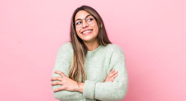 Bella donna ispanica che si sente felice, orgogliosa e speranzosa, chiedendosi o pensando di copiare lo spazio con le braccia incrociate