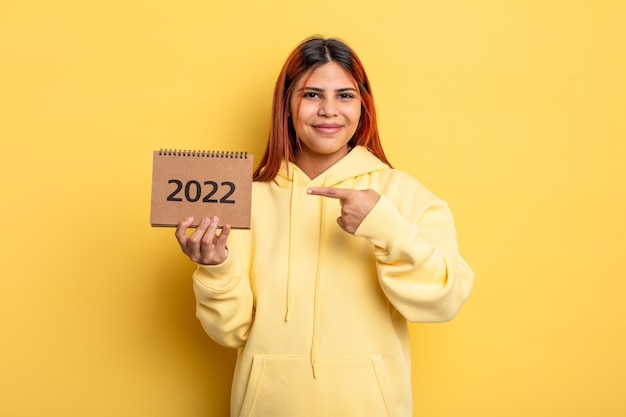 Bella donna ispanica che tiene un calendario o un'agenda 2022