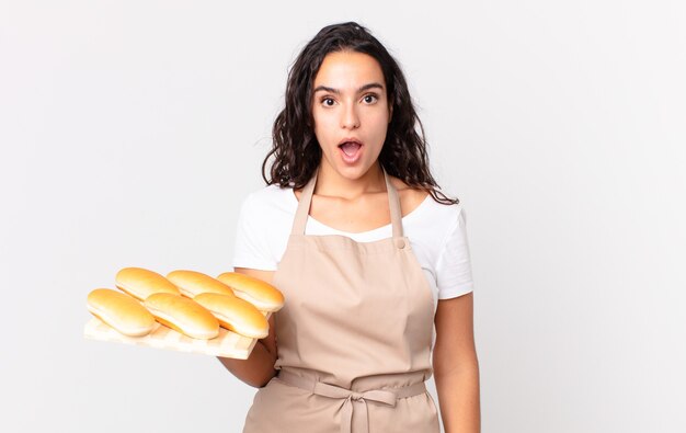 bella donna ispanica chef che sembra molto scioccata o sorpresa e tiene in mano un panino troy