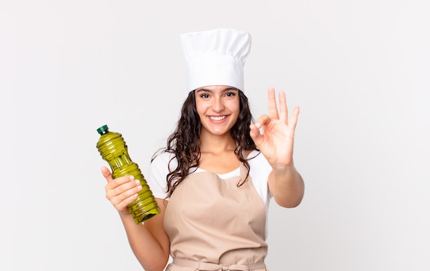 Bella donna ispanica chef con in mano una bottiglia di olio d'oliva