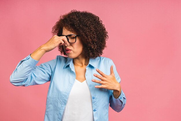 Bella donna ispanica in piedi sopra isolato su sfondo rosa annusare qualcosa di puzzolente e disgustoso odore intollerabile trattenere il respiro con le dita sul naso cattivo odore