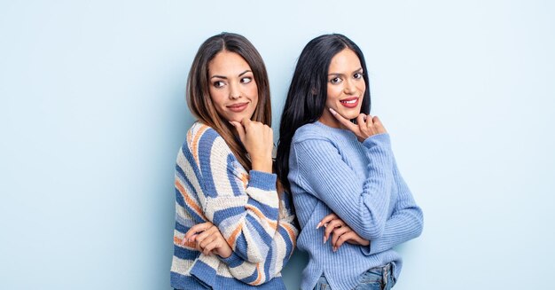 Bella donna ispanica sorridente con un'espressione felice e sicura con la mano sul mento coppia di amici concetto