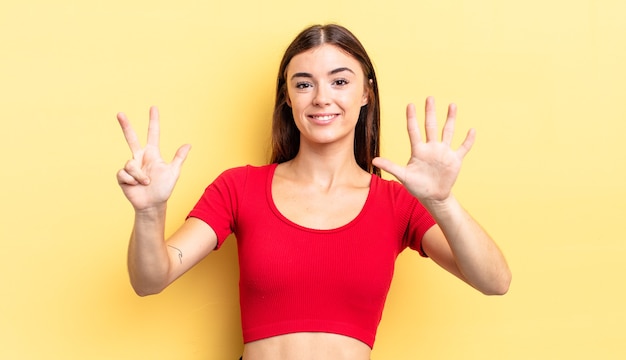 Bella donna ispanica sorridente e dall'aspetto amichevole, che mostra il numero otto o ottavo con la mano in avanti, conto alla rovescia