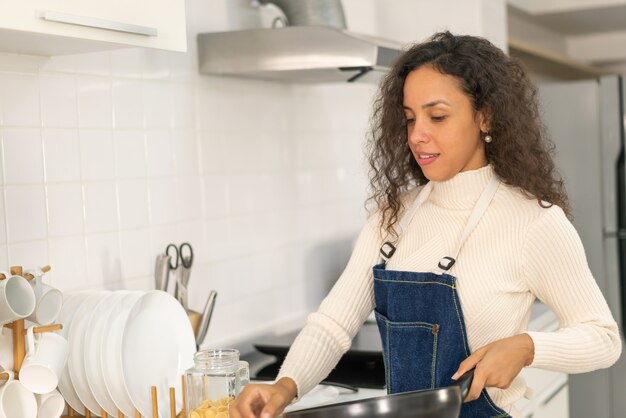 Bella donna latina che cucina in cucina