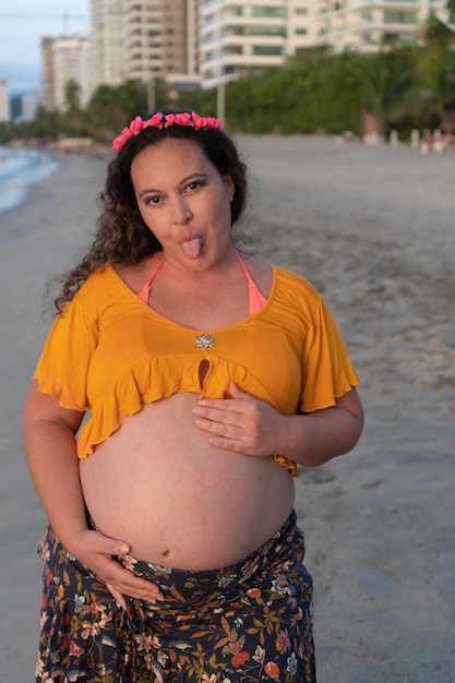 Bella donna latina incinta sulla spiaggia