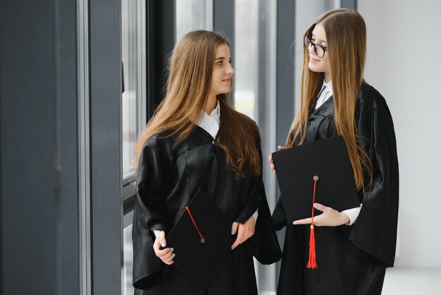 Bella donna laureata in piedi fuori da un gruppo di studenti