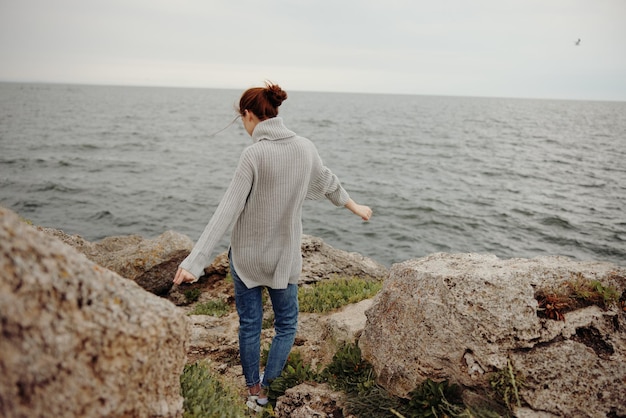 Bella donna maglioni mare nuvoloso ammirando la natura Stile di vita vista posteriore