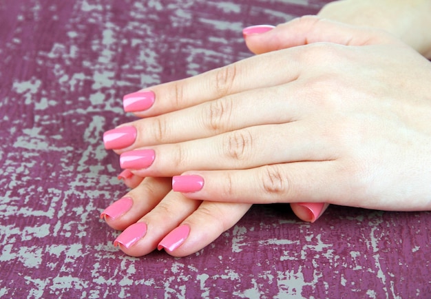 Bella donna mani con manicure rosa su sfondo colorato