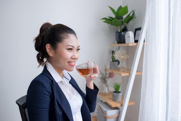 Bella donna matura che beve una tazza di tè nel suo ufficio. (con copia spazio.)