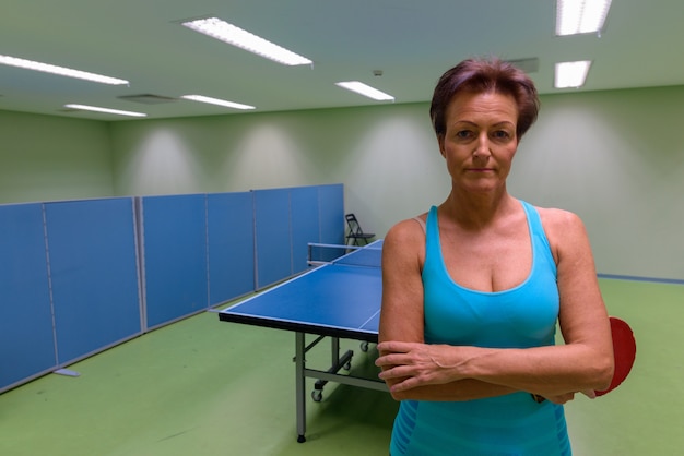 Bella donna matura che gioca ping-pong all'interno