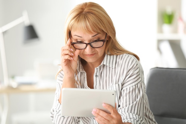 Bella donna matura con il computer tablet a casa