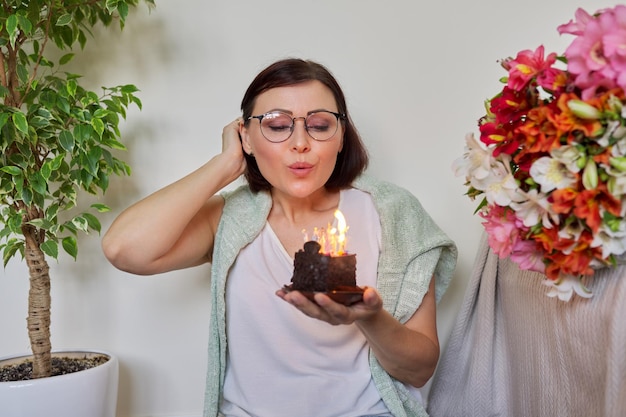 Bella donna matura con una piccola torta di compleanno con candele accese