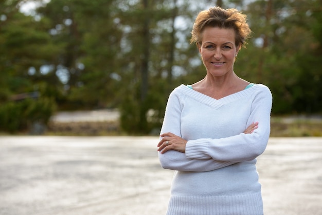 Bella donna matura felice con i capelli corti che sorride al parco all'aperto