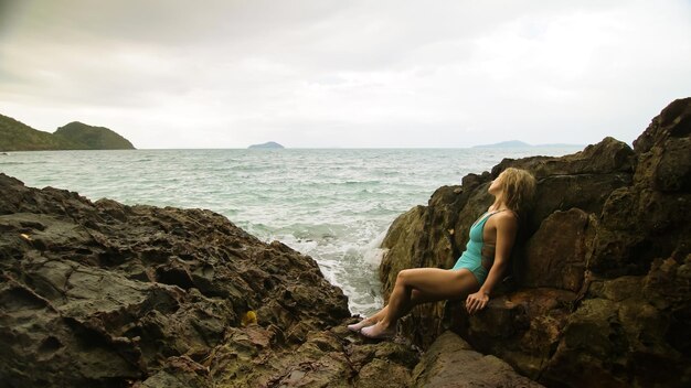 Bella donna medita rilassa sulla roccia crack scogliera collina in tempestosa mattina mare nuvoloso Concetto femminile sessuale vaginale salute igiene femminile libertà fresca Madre dell'oceano dà alla luce lui