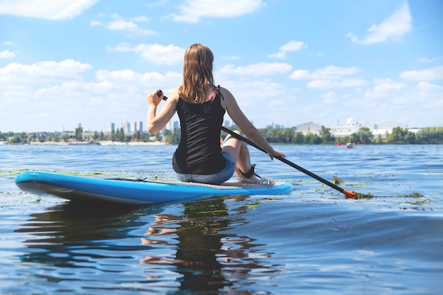 Bella donna millenaria su una tavola SUP sul fiume