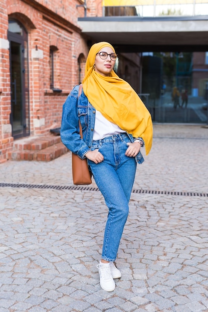 Bella donna musulmana araba che indossa l'hijab giallo, ritratto femminile alla moda sulla strada della città.